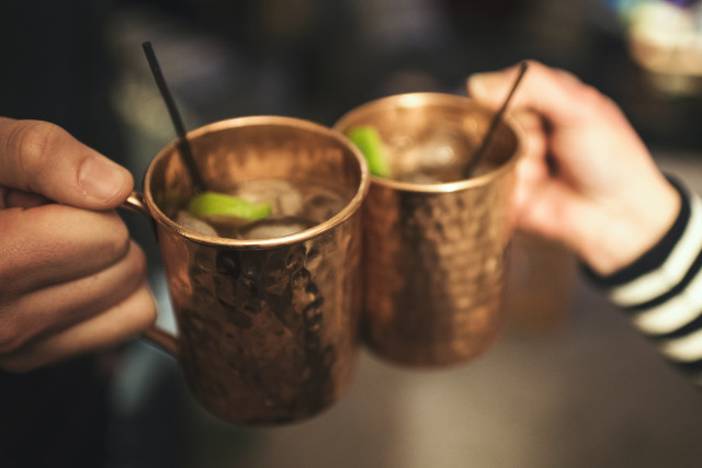 Two people cheers copper mugs